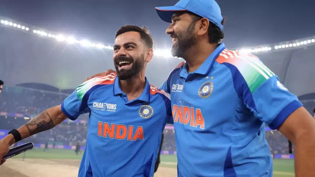 Virat Kohli and Rohit Sharma in India shirts, smiling with arms around each other at a floodlit stadium